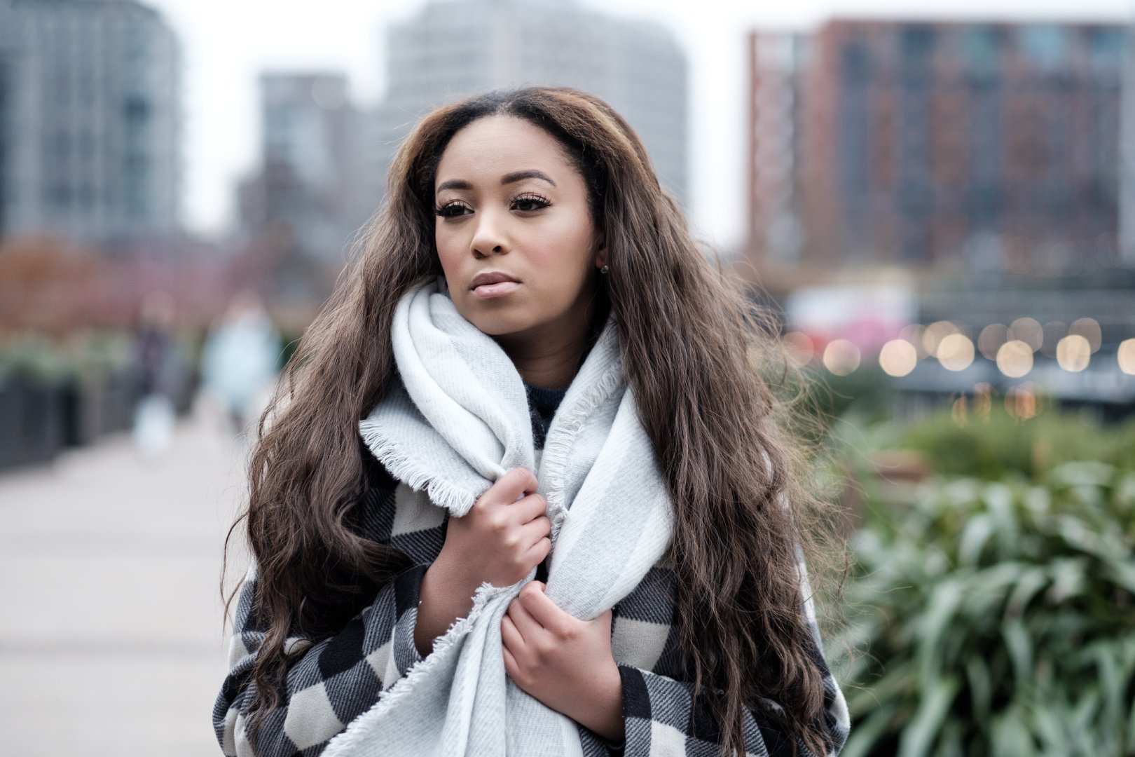Portrait of young black woman in a very cold winter day. She is wearing coat and scarf.