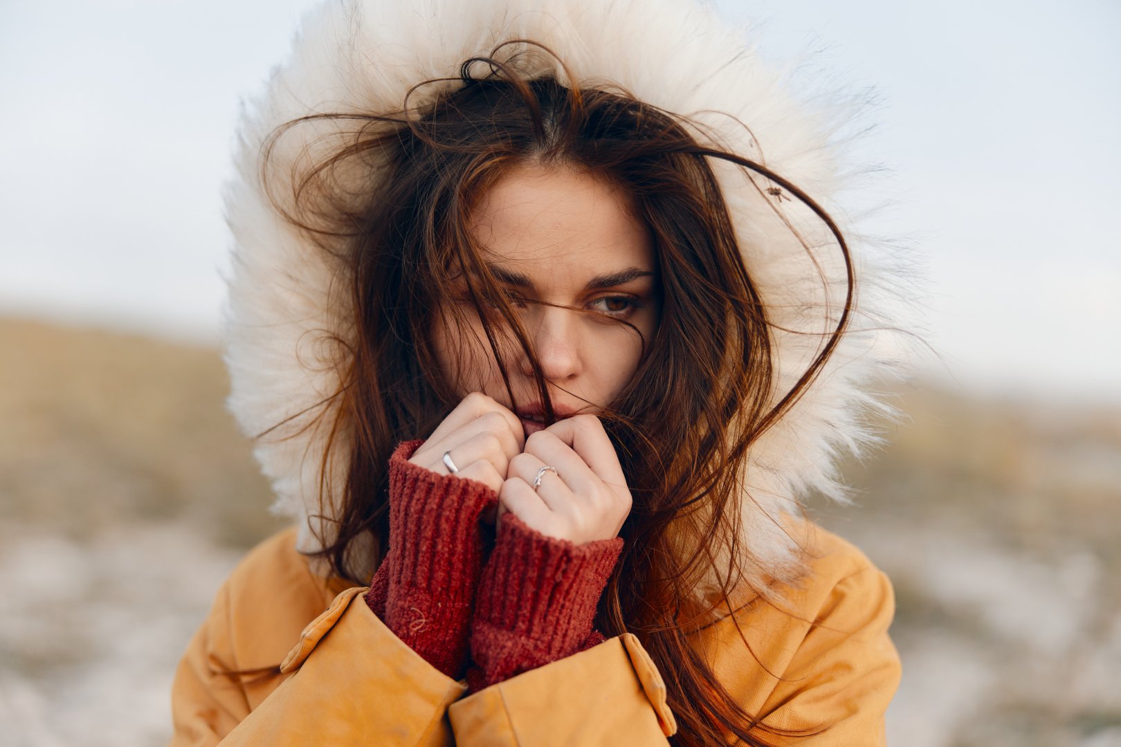 Woman in yellow coat and red gloves emotionally reacting to the beautiful scenery in nature